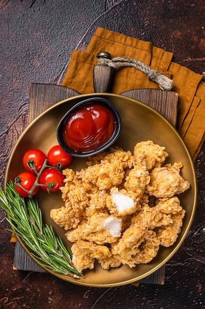 Knuspriges Popcorn-Huhn mit Barbecue-Sauce in einer Platte mit dunklem Hintergrund Draufsicht