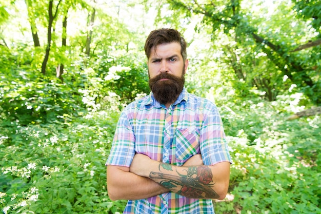 Öko-Lebensstil Vereint mit der Umwelt Schöner Holzfäller Mann bärtiger Hipster mit grünen Bäumen Hintergrund Kerl entspannt sich in der Sommernatur Mann Bart und Schnurrbart im Sommerwald Sommerurlaubskonzept