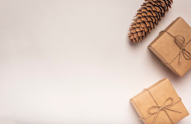 Öko weißer Hintergrund mit zwei Geschenkboxen mit Juteschnurbögen und Tannenzapfen mit Kopienraum.