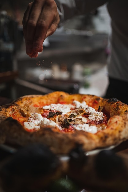 Foto koch beendet die zubereitung einer köstlichen pizza in einem italienischen restaurant