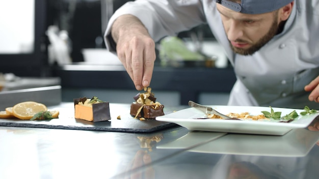 Koch dekoriert Kuchen in der Küche Nahaufnahme des Kochs, der in Zeitlupe ein Dessert zubereitet
