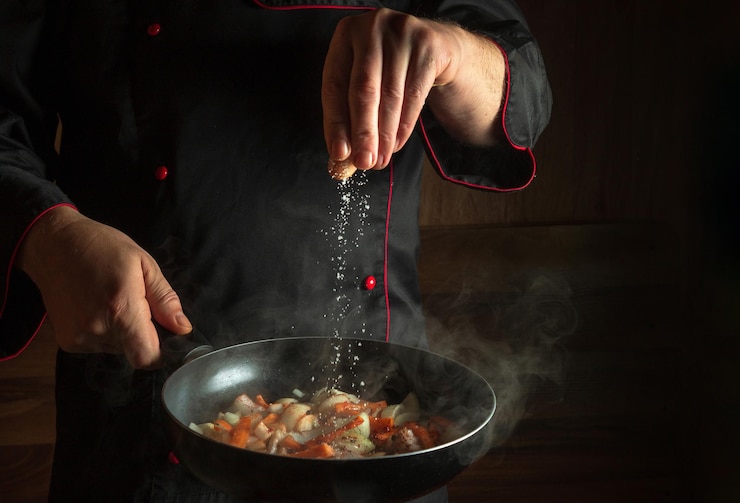 Foto koch fügt salz zu einer dampfenden heißen pfanne menüidee für ein hotel mit werbefläche asiatische nationale küche platz für restaurantmenü oder rezept