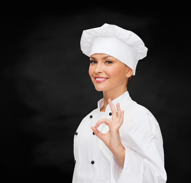 Koch-, Gesten- und Lebensmittelkonzept - lächelnde Köchin, die ein ok-Handzeichen zeigt
