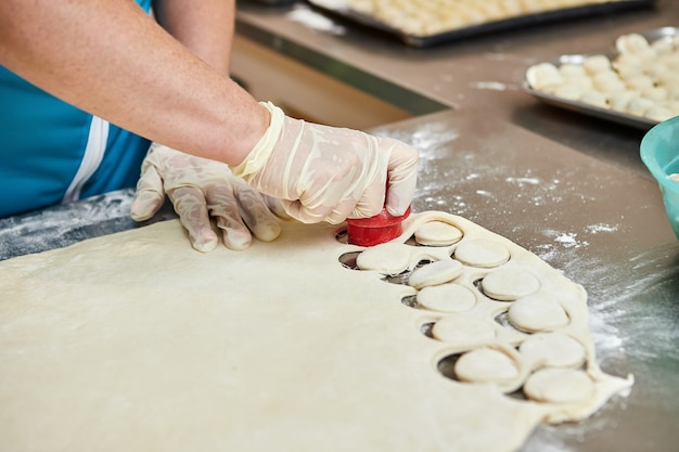 Koch Hände kochen Knödel auf dem Hintergrund von Schneidebrettern mit handgemachten, Ravioli und Khinkali bestreut mit Mehl auf einem Tisch. Leckeres hausgemachtes Essen.