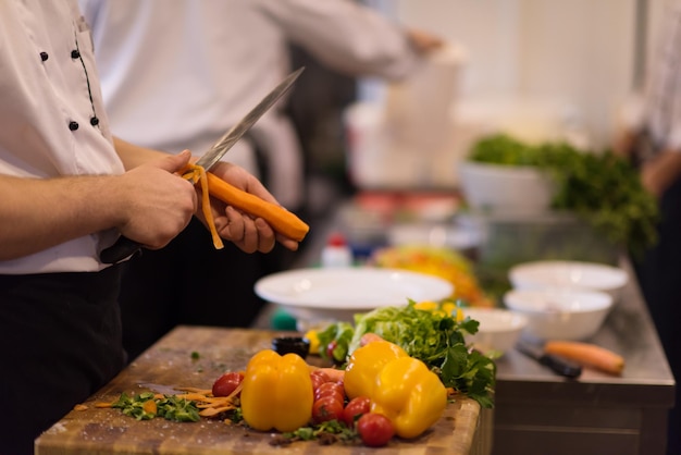 Koch Hände schneiden Karotten auf einem Holztisch Vorbereitung für das Essen im Restaurant