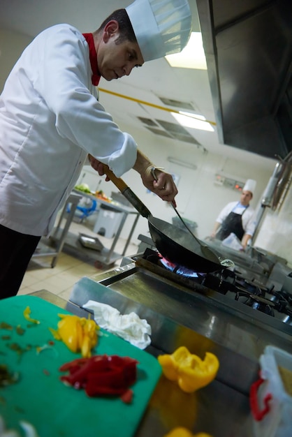 koch in der hotelküche bereitet gemüsegerichte mit feuer zu