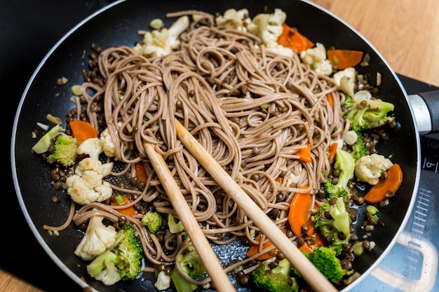 Foto koch in der küche bereitet japanische buchweizenpasta mit linsen vor