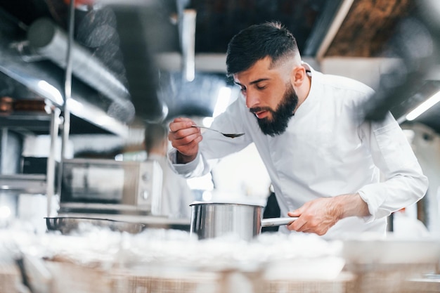 Koch in weißer Uniform, der Essen in der Küche kocht Beschäftigter Tag bei der Arbeit