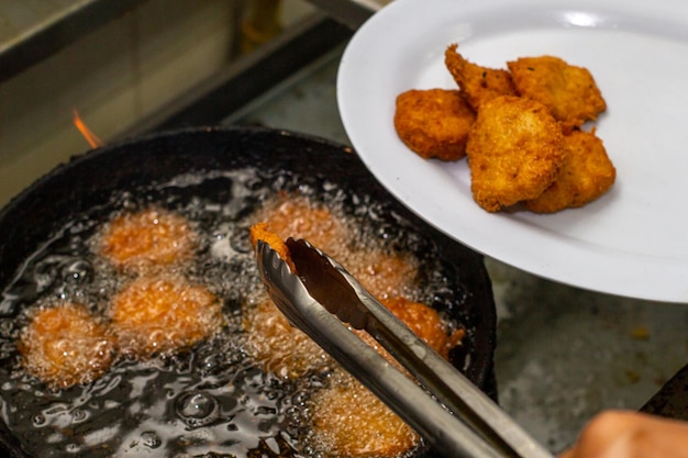 Foto koch joven cocinando arepa frita en aceite, tipica dominica latinoamericana