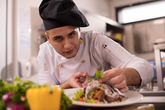 Koch Koch Dekoration Garnierung zubereitete Mahlzeit Gericht auf dem Teller in der gewerblichen Küche des Restaurants