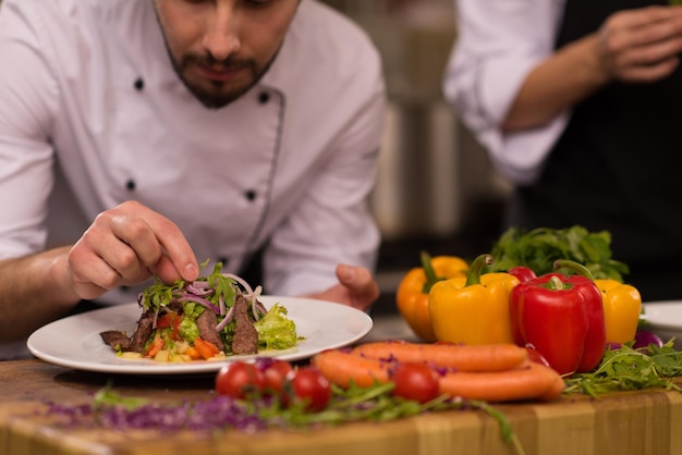 Koch Koch Dekoration Garnierung zubereitete Mahlzeit Gericht auf dem Teller in der gewerblichen Küche des Restaurants