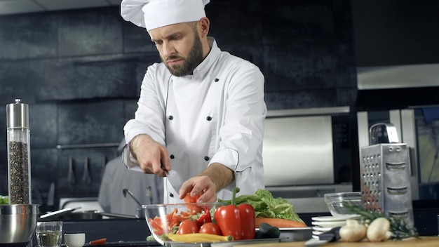 Koch kocht in der Restaurantküche. Professioneller Koch bereitet frischen Salat zu