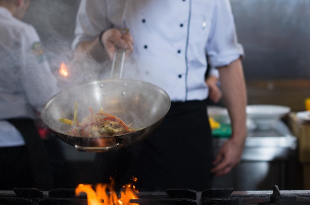 Koch kocht und flambiert Essen in der Restaurantküche