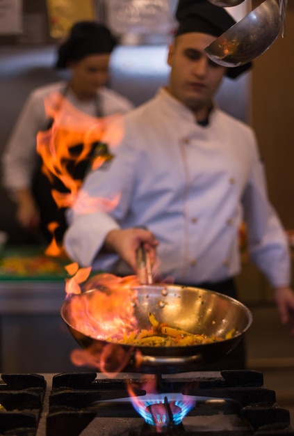 Koch kocht und flambiert Essen in der Restaurantküche