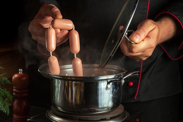 Koch legt Wiener Würstchen in einen Topf Arbeitsumgebung in der Küche eines Restaurants oder Cafés Frühstück oder Abendessen zubereiten