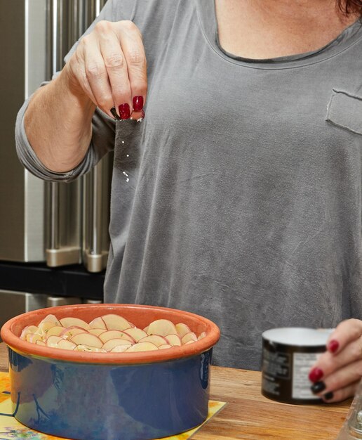 Koch salzt Kartoffelgratin in blumenförmiger Keramikschale