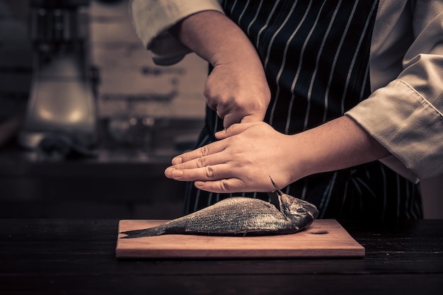 Koch schneidet den Fisch auf einem Brett