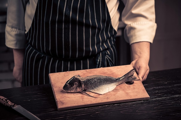 Koch schneidet den Fisch auf einem Brett