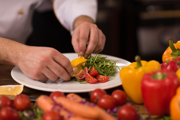 Koch serviert Gemüsesalat auf dem Teller in der Restaurantküche