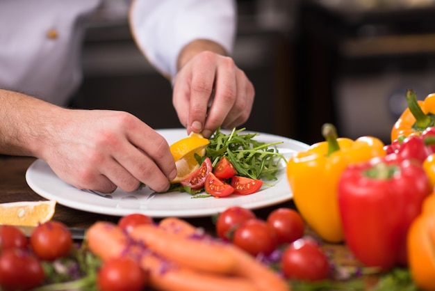 Koch serviert Gemüsesalat auf dem Teller in der Restaurantküche