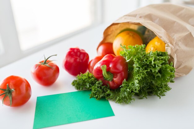 Kochen, Ernährung, vegetarisches Essen und gesundes Ernährungskonzept - Nahaufnahme einer Papiertüte mit frischem, reifem, saftigem Gemüse und Grünzeug auf dem Küchentisch zu Hause