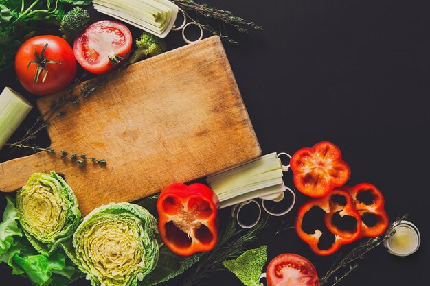 Kochen gesunder Lebensmittelhintergrund. Salat mit frischem Bio-Gemüse, Grüns und Kräutern auf Schwarz vorbereiten. Natürliche Nahrung mit Kopienraum.