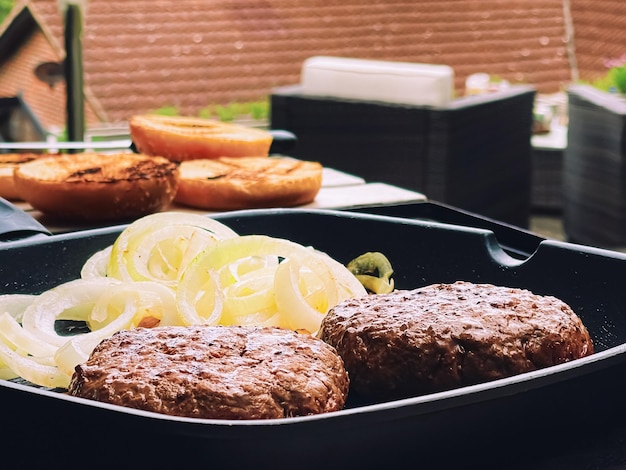 Kochen Hackfleisch Burger auf gusseisernen Grillpfanne im Freien rotes Fleisch auf der Pfanne Grillen von Speisen im Garten Englisches Landleben