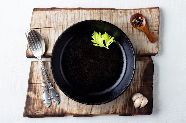 Kochen Hintergrundkonzept. leere rustikale schwarze gusseiserne Platte, Gewürze und Besteck.