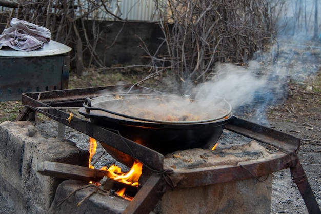 Kochen in einem kessel auf dem scheiterhaufen. essen im freien. leben in der natur.