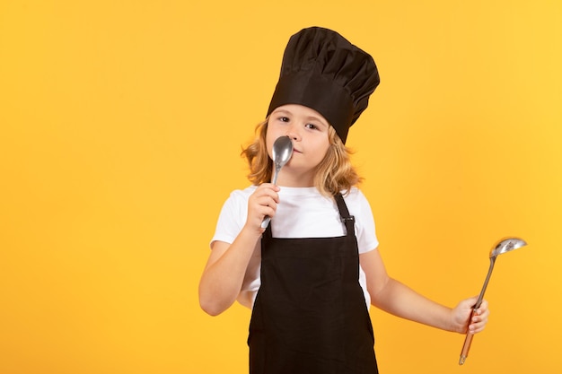 Kochen kulinarisch und Kinder Kleiner Junge in Kochmütze und Schürze auf Studio isoliertem Hintergrund