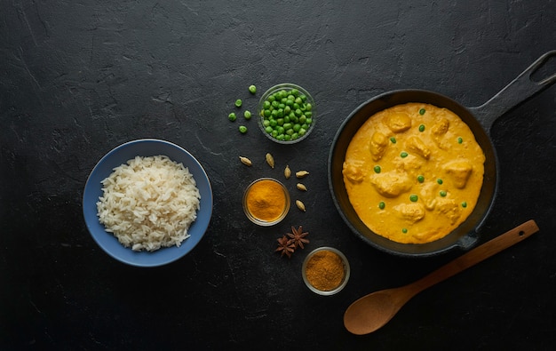 Kochen leckeres Butter-Hühnchen-Curry-Gericht mit Reis in einer gusseisernen Pfanne