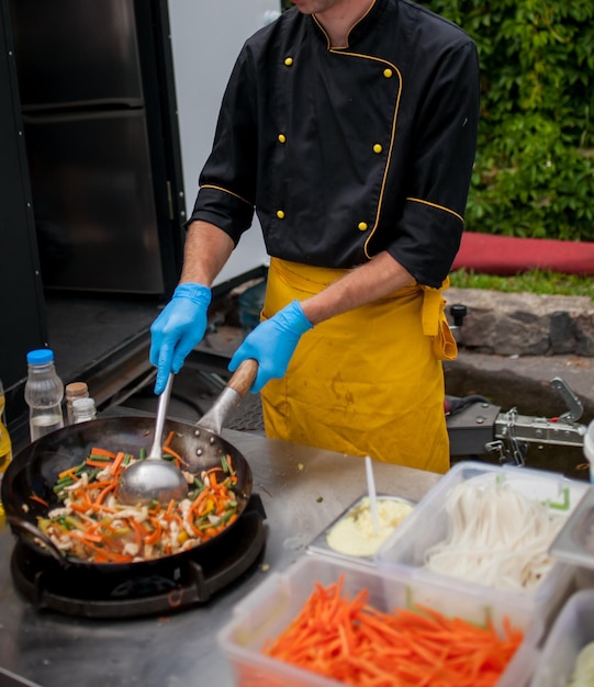 Kochen Sie Bratgemüse in einer Wokpfanne auf Feuer Küchenchef rührt Gemüse im Wok