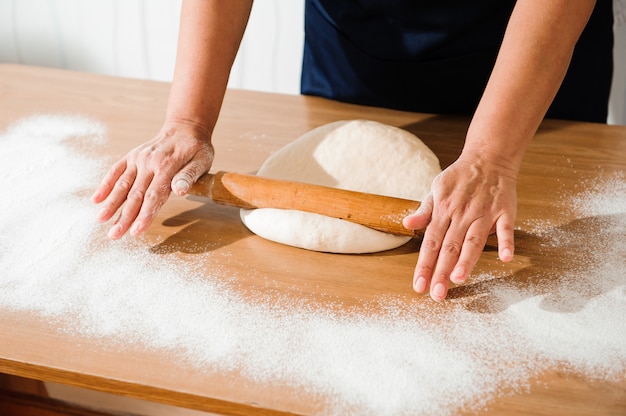 Kochen Sie die Hände, die Teig kneten, Stück Teig mit weißem Weizenmehl besprühen.