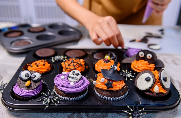 Kochen Sie köstlichen hausgemachten Kuchen und dekorieren Sie Cupcakes für Halloween festlich.