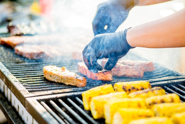 Kochen von GrillfischBehandschuhte Hände drehen Fischstücke auf dem Grill