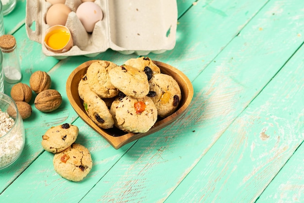 Kochen von Haferkeksen mit kandierten Früchten und Walnüssen Eier Hafermehl Zucker Gewürze und Küchenutensilien auf einem alten Holz Backrezept oder Konzept für die Herstellung von Konditoreien im Klassenzimmer