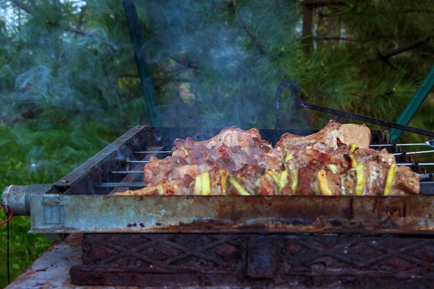 Foto kochen von kebabs auf einem grill mit rauch frisches braunes bbq-fleisch, das auf einem außengrill gekocht wird