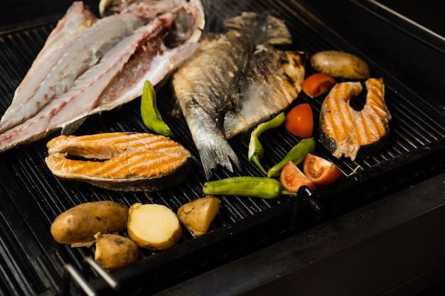 Kochen von Meeresfrüchten aus Lachs, Wolfsbarsch und Gemüse. Grillen von Fisch mit Chilikartoffeln und Tomaten.