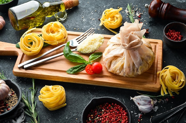 Foto kochen von pasta carbonara mit ei und parmesan-käse-basilikum auf schwarzem steinhintergrund draufsicht rustikaler stil