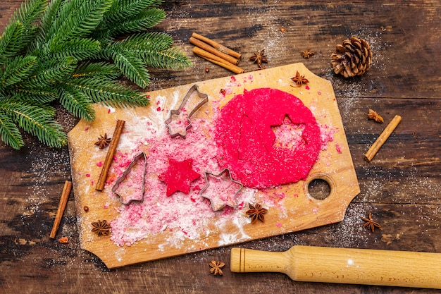 Kochen von roten Ingwerplätzchen. Traditionelles Weihnachtsgebäck. Tannenbaum, Gewürze, Ausstechformen, roher Teig, Nudelholz, Holzbretter