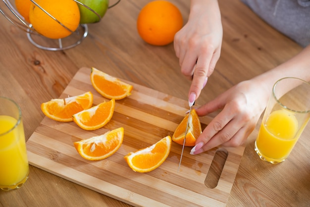 Kochen von Speisen und Konzept von Veganismus und gesundem Essen, Nahaufnahme der weiblichen Hand, die Orange auf Scheiben schneidet