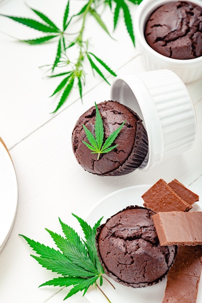 Kochen von Unkrautmuffins in einer Auflaufform mit Cannabis oben, Cannabisblättern, Hanfzweigen auf dem Tisch