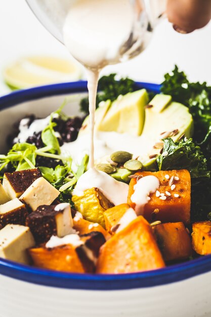 Kochen von veganem Salat mit schwarzem Reis, Avocado, Tofu, Süßkartoffel, Grünkohl und Tahini-Dressing