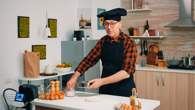 Kochen vor professioneller Kamera beim Filmen neuer Rezepte. Pensionierter Blogger-Koch-Influencer, der Internet-Technologie verwendet, kommuniziert und Blogging in sozialen Medien mit digitaler Ausrüstung fotografiert