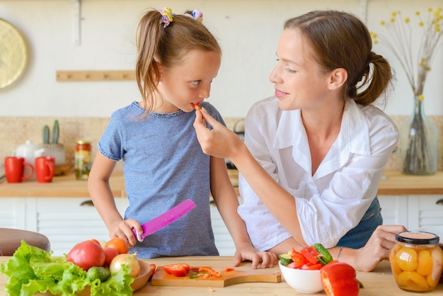 Kochkurs Glückliche geduldige Mutter bringt der kleinen Tochter bei, gesundes Essen zu kochen