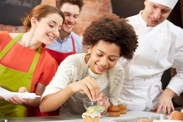 kochkurs, kulinarisch, bäckerei, essen und personenkonzept - glückliche gruppe von freunden und männlicher koch backen in der küche