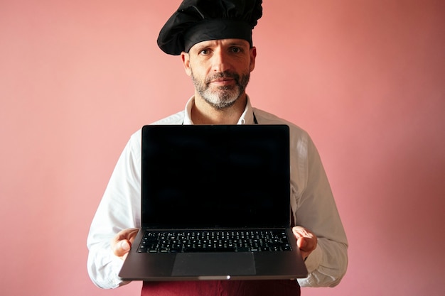 Kochmann mit Laptop mit rosa Wand