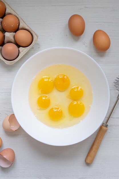 Kochprozess Eier in einer weißen Schüssel auf dem Frühstückskonzept mit flacher Ansicht des Küchentisches