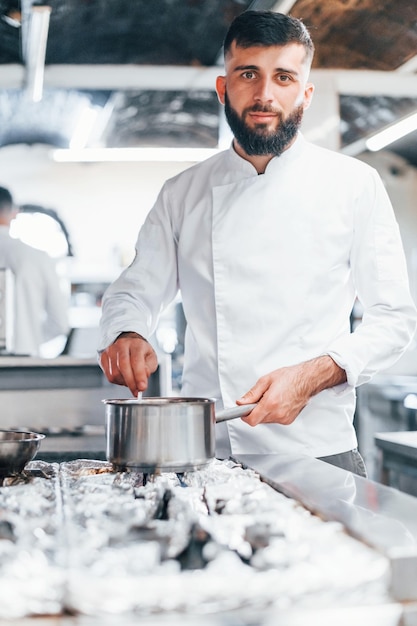 Kocht köstliche Suppe Koch in weißer Uniform kocht Essen in der Küche Beschäftigter Tag bei der Arbeit