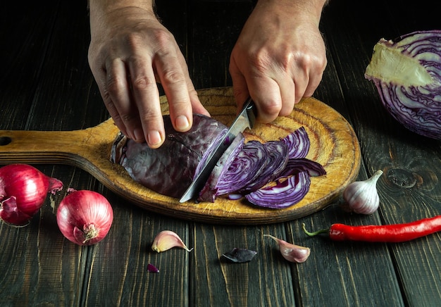 Köchens Hände mit einem Messer geschnitten Rotkohl auf einem Schneidbrett Gemüsesalat in der Küche Kochen Die Idee einer Gemüsediät aus Bauernprodukten